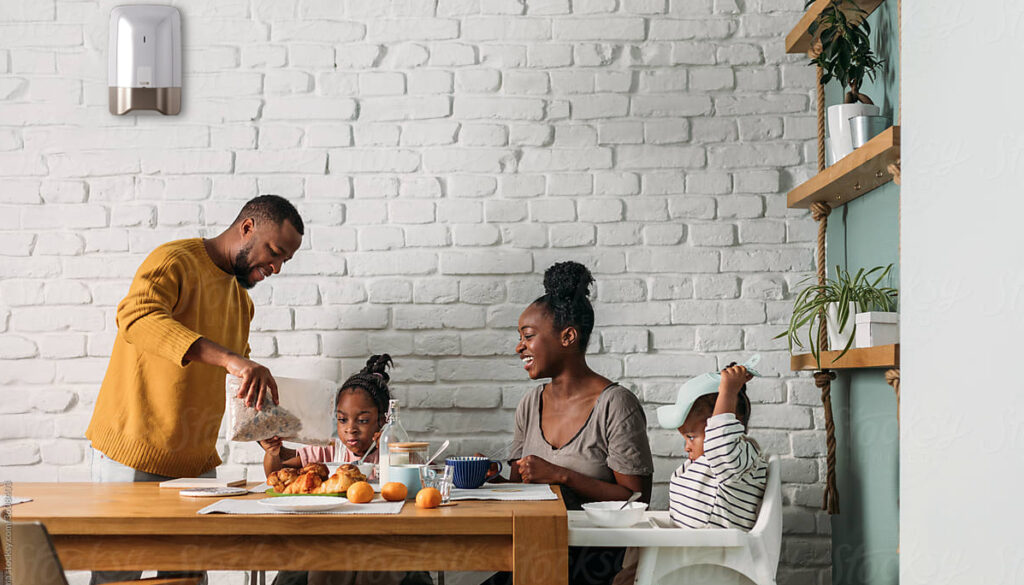 Une famille qui prend son petit déjeuner dans une pièce de vie équipé d'une centrale sirène cs8000 de delta dore.