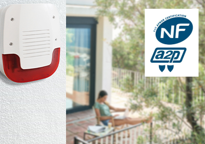 Un sirène extérieure installé sur le mur d'une habitation proche d'une terrasse et le logo que le produit est certifié NFa2p